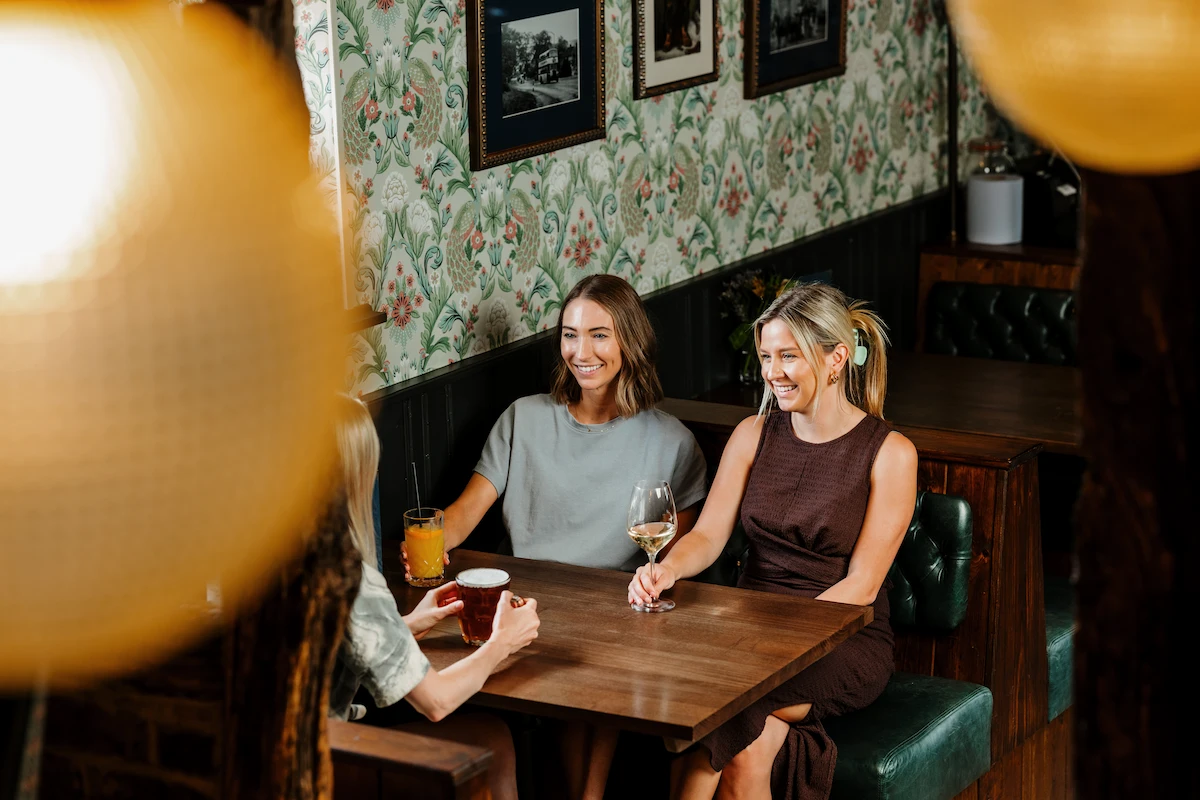 People enjoying drinks whilst sat at a table at the Peacock at Owler Bar