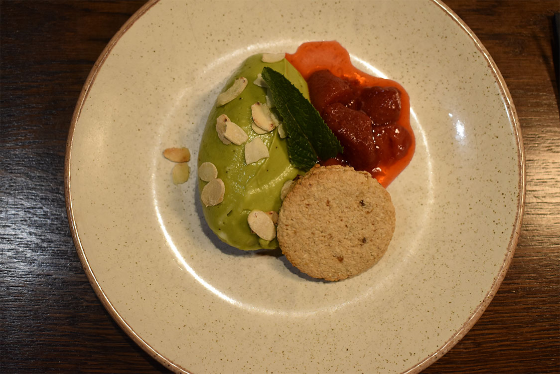 Kiwi-Matcha-Mousse Kiwi and Matcha mousse with flaked almonds, strawberry compote and an oat biscuit (GF) (VE)